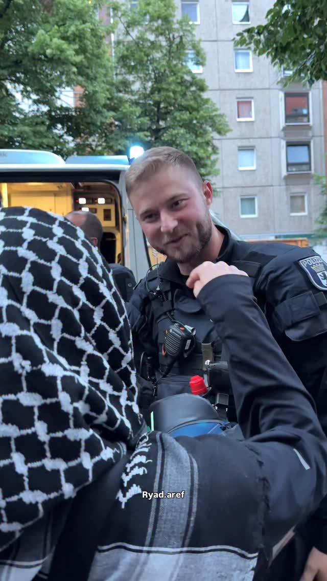 During an exchange with Berlin police, a demonstrator requested information to file an official complaint, while the officer pointed to his identification number. The moment was captured on camera during the protest.